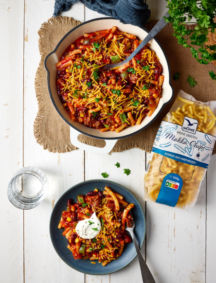 Große Schüssel mit Nudelgericht nach mexikanischer Art, darunter ein Teller damit und daneben Möwe Makka Chips. Siehe Rezept.