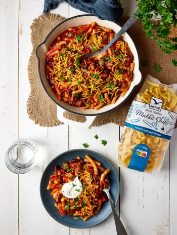 Große Schüssel mit Nudelgericht nach mexikanischer Art, darunter ein Teller damit und daneben Möwe Makka Chips. Siehe Rezept.