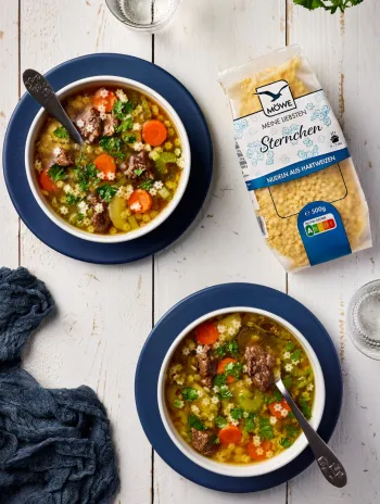 Zwei Schüsseln mit einer Gemüse-Rind-Suppe. Darin Sternchennudeln. Daneben eine Packung Möwe Meine Liebsten Sternchen Suppennudeln.