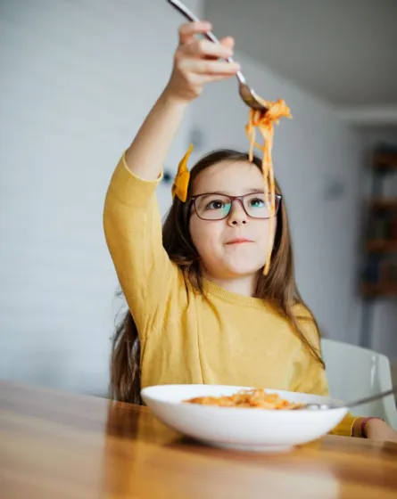 Ein Kind isst Spaghetti.