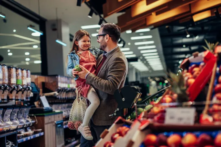 Ein Vater ist mit seiner Tochter im Supermarkt einkaufen.